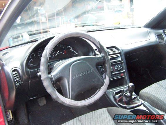 Car interior showing dashboard, steering wheel with 'PROBE' logo, gear shift, and seats