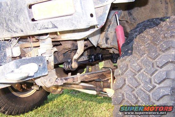 Close-up of a vehicle's front suspension, showing leaf springs, shock absorber, and steering linkage
