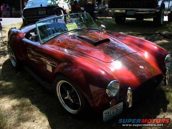 Red convertible sports car with racing stripes and scoop on hood