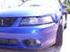 2003 Ford Mustang - The front end of a blue Ford Mustang is captured in this close-up shot, highlighting its distinctive grille and headlights.