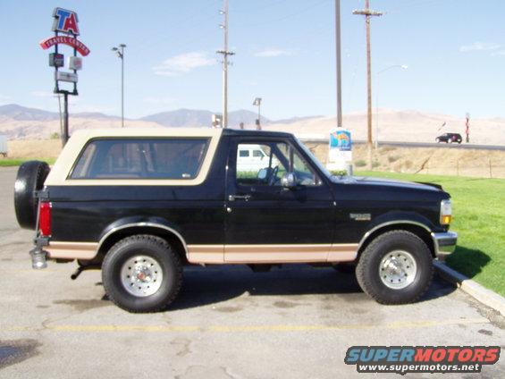 Black and tan Ford Bronco parked on asphalt, side view