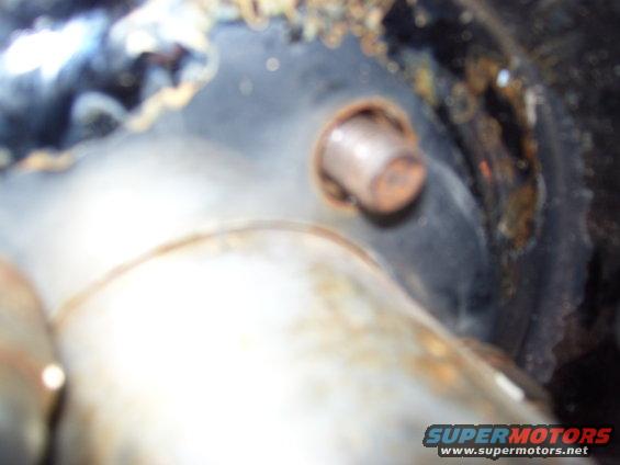 Rusty bolt on black metal surface with SUPERMOTORS.NET watermark