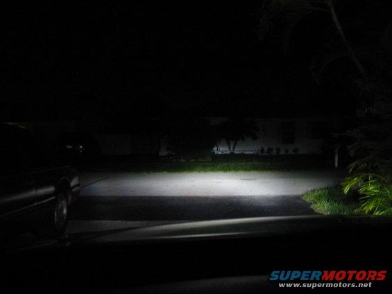 Car's headlights illuminate a dark driveway at night