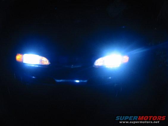 1995 Ford Thunderbird front with bright headlights on at night