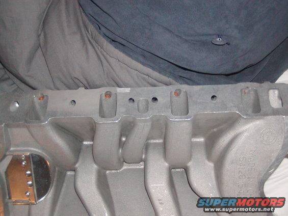 Close-up of an aluminum intake manifold with visible ports and some text stamped on the side