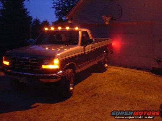 1992-1997 Ford F-Series truck with cab lights on, parked by a garage