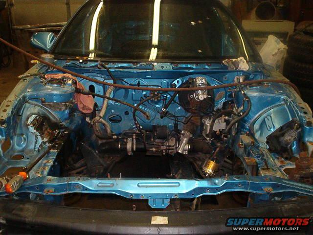 Blue engine bay with engine removed, showing wiring and hoses