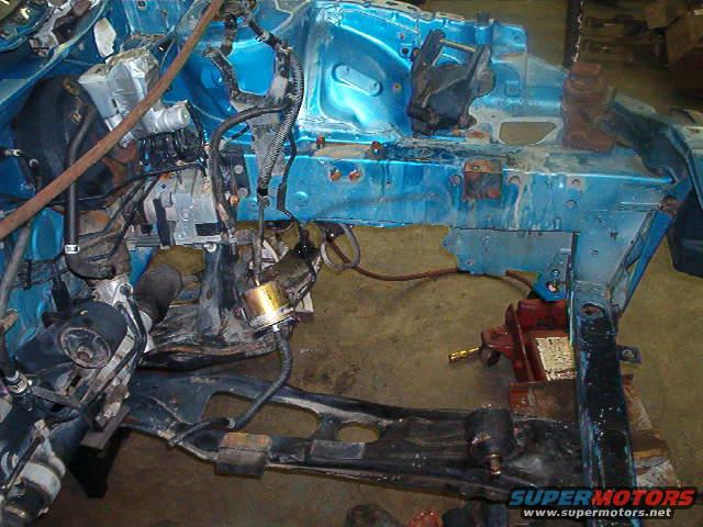 Disassembled blue vehicle frame with engine components and wiring visible