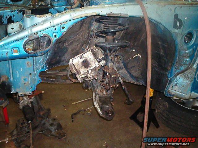 close-up of car's front suspension and wheel well area, appears to be disassembled
