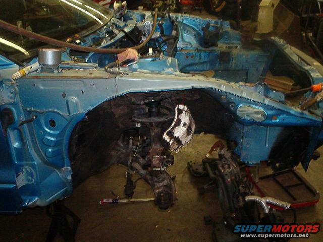 Disassembled blue car chassis, front view, showing suspension and engine bay components