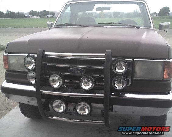 Dark brown Ford truck front view with a chrome grille guard and multiple round lights