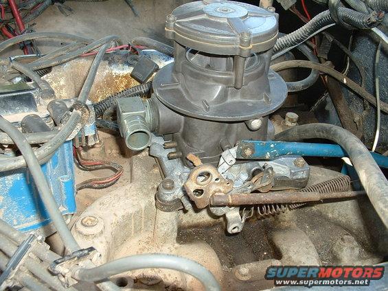 Close-up of a carburetor with associated engine wiring and linkages