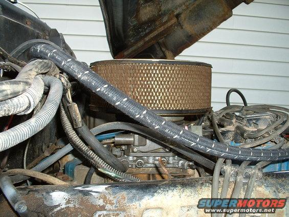 engine bay showing carburetor, air filter, and hoses