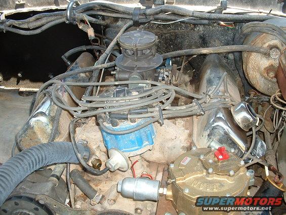 Engine bay showing carburetor, distributor, and a propane conversion tank