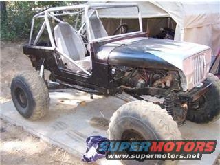 Jeep CJ-7 body undergoing modification, showing roll cage and exposed engine