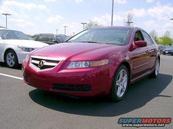 Red sedan parked in a lot, with a white car to its left and a dark SUV behind it