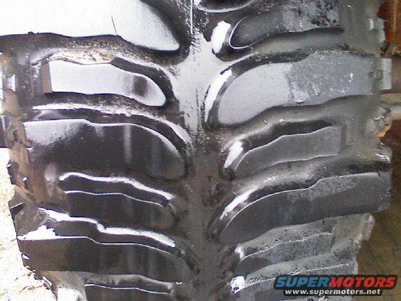 Close-up of a large tire tread pattern with Supermotors.net logo in the corner