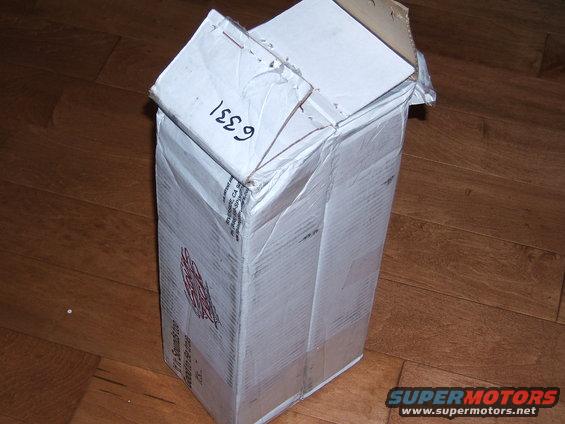 Cardboard box with handwritten '6331' and red logo on wooden floor