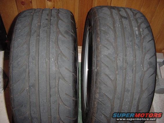 Two worn tires, one with a visible rim, against a wood-paneled background