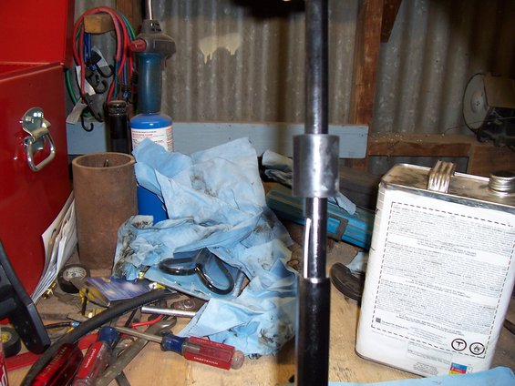 Workbench with tools, blue shop towels, and a metal can with text