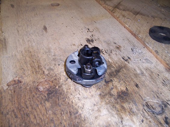 Steering column U-joint with black metal yokes and a silver metal housing, resting on a wooden surface