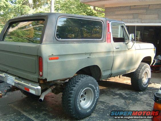 Ford Bronco parked in driveway, side view showing rear quarter panel and lifted suspension