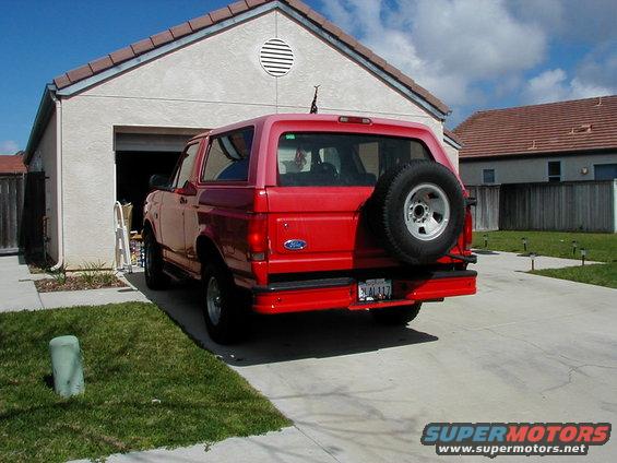 Red 1995 Ford Bronco parked in driveway, spare tire mounted on rear door