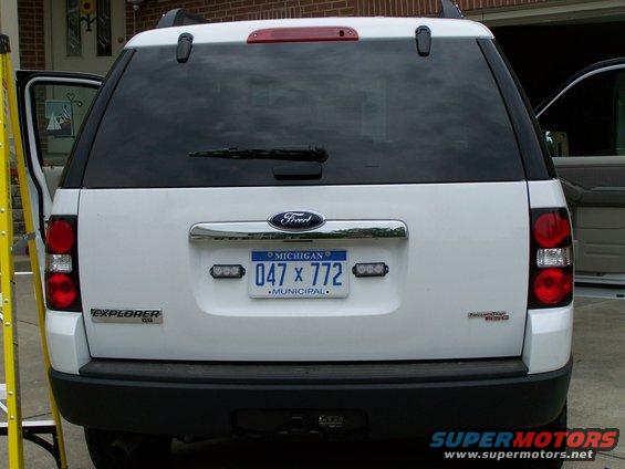 Rear of white Ford Explorer with Michigan license plate 047 x 772. Emergency lights are mounted on the bumper