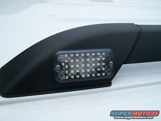 Close-up of an aftermarket LED light bar mounted on a black roof rack rail