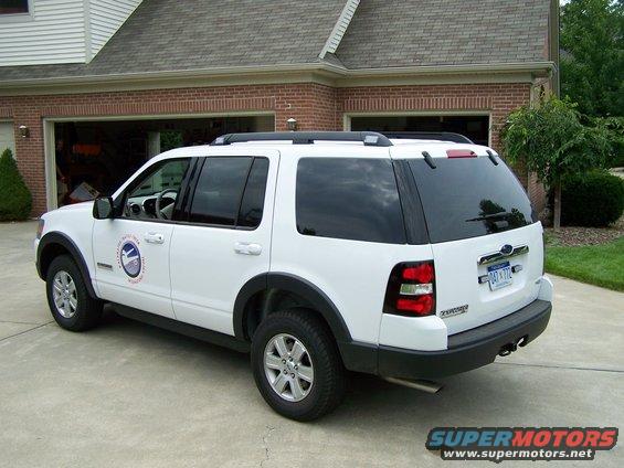 White Ford Explorer rear 3/4 view. Visible logo on door and license plate