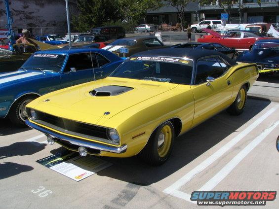 Yellow 1970 Plymouth Barracuda with black vinyl roof and hood scoop parked in a lot