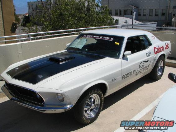 White 1969 Ford Mustang Cobra Jet with black hood scoop and racing decals