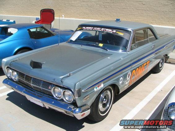Gray Mercury Comet with orange "COMET" lettering on the side, parked next to a blue car