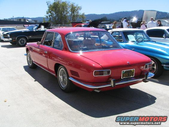 Red coupe with chrome trim and wire wheels, parked outdoors