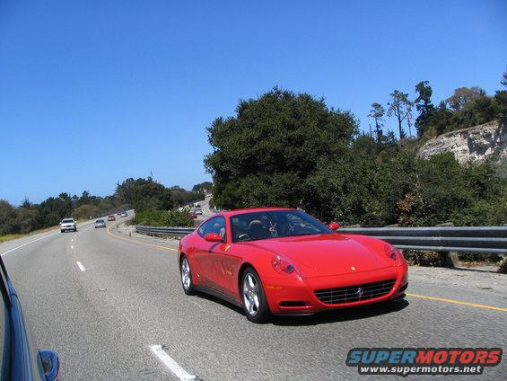 Red Ferrari coupe driving on a highway with other cars visible
