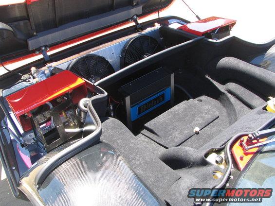 1986 Pontiac Fiero engine bay showing fans, red engine cover, and McIntosh audio amplifier