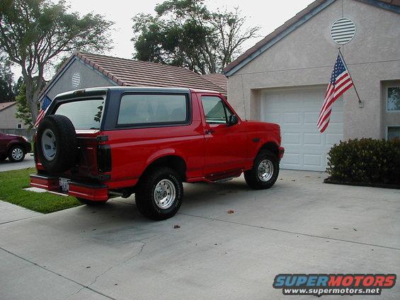 Red 1995 Ford Bronco parked in driveway with spare tire on rear door