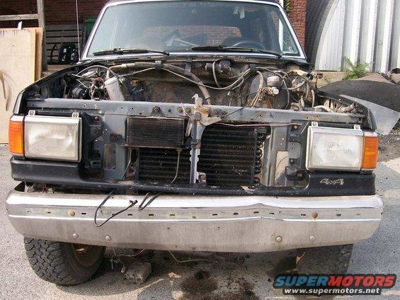 Front of a 1989 Ford Bronco with hood open and grille removed, showing engine components