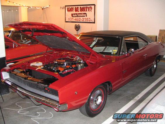 Red 1968 Dodge Charger with hood open, showing engine. Another red car is behind it