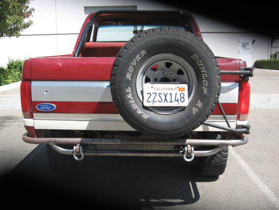 Red and silver Ford Bronco rear with spare tire mounted, custom bumper, and California license plate