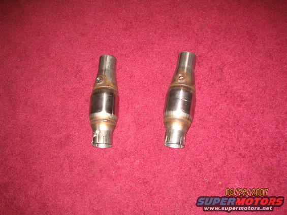 two metal catalytic converters on a red surface