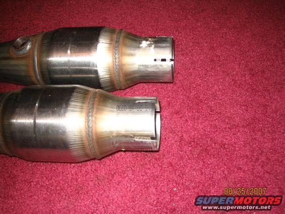 Two catalytic converters with visible part numbers and date stamps