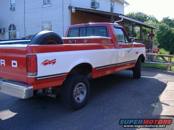 1989 Ford F-150 pickup truck, red and white two-tone paint, 4x4 decal on fender, spare tire in bed