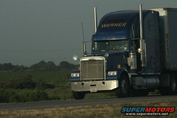 Blue Werner semi-truck driving on a highway with a trailer
