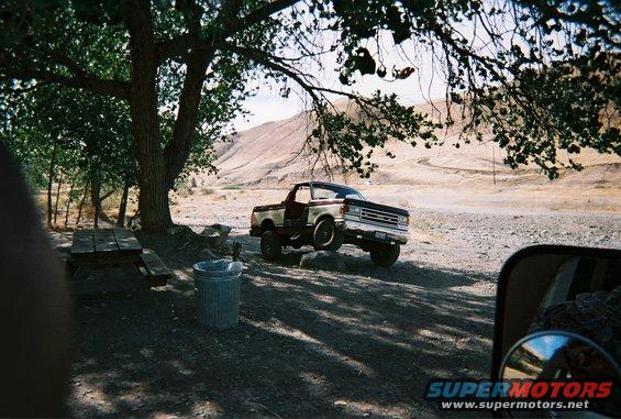 1987 Ford F-Series truck parked off-road under a tree