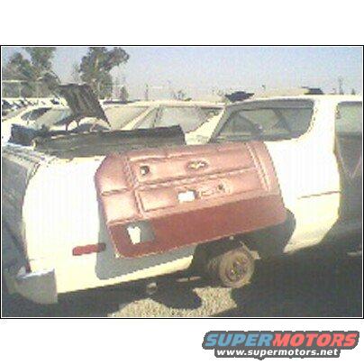 car door resting on a white car in a junkyard