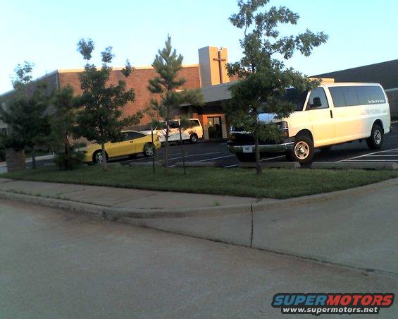 White van parked next to a yellow car in front of a building