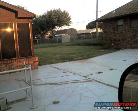 Backyard scene with a house, lawn, shed, and fence