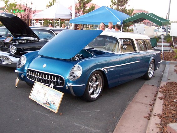 Blue and white 1955 Chevrolet Nomad wagon with hood open, parked next to a black car