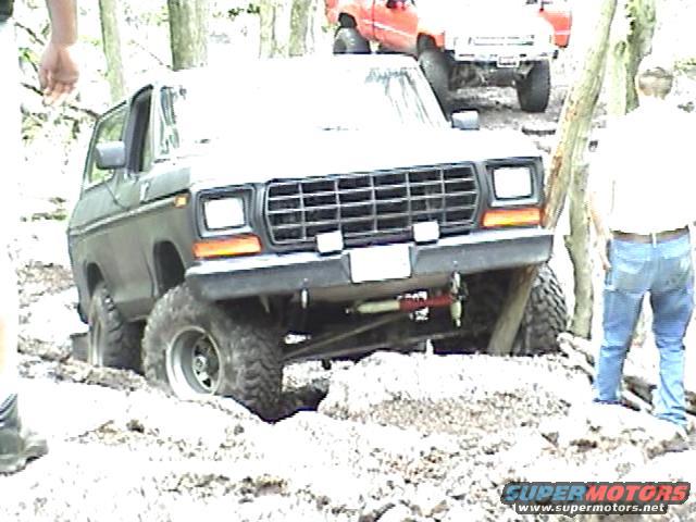 1978 Ford Bronco navigating muddy terrain with another vehicle behind it